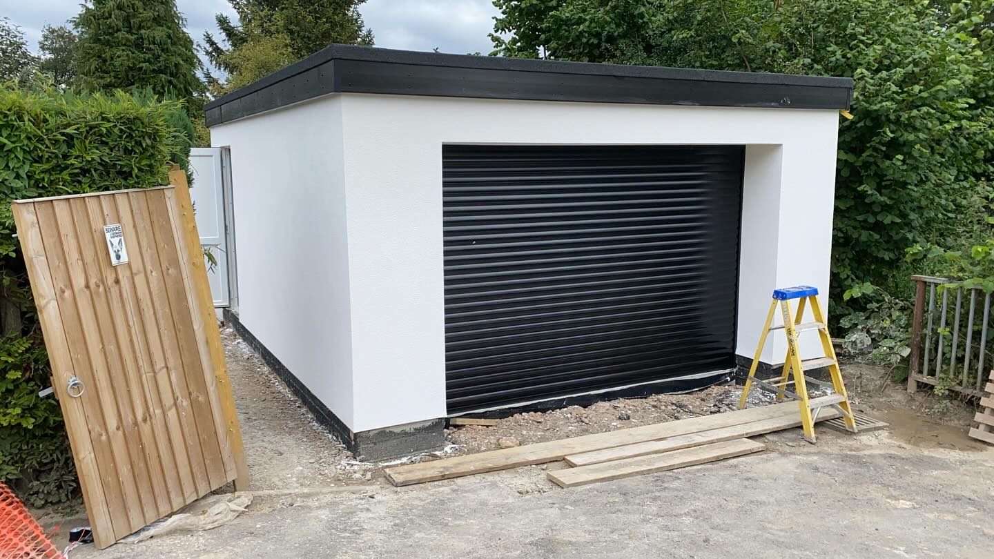 Newly rendered garage with black roller door