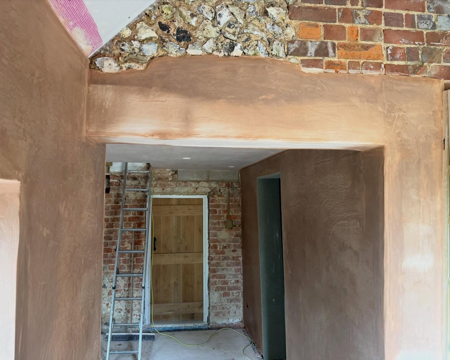 Freshly plastered hallway with flint and brick feature